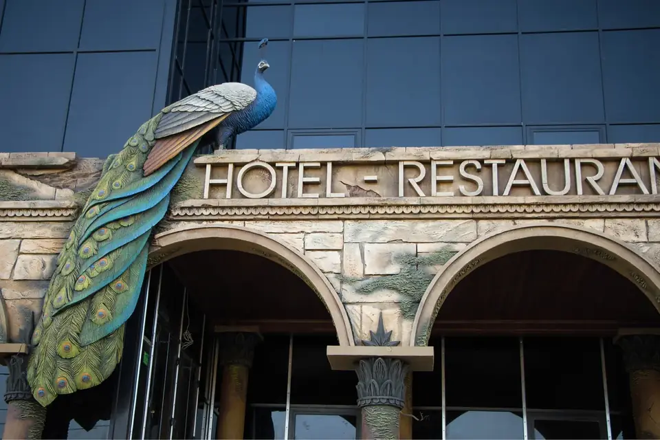 Fasada hotelu i restauracji z monumentalną rzeźbą pawia nad wejściem